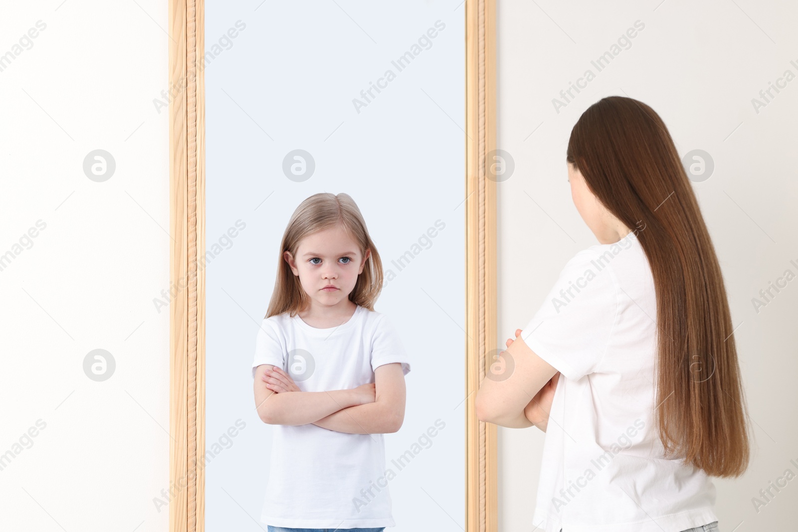 Young woman seeing herself as child in mirror. Conceptual collage about past and future, flow of time, age Image of Young woman seeing herself as child in mirror. Conceptual collage about past and future, flow of time, age