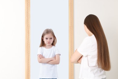 Image of Young woman seeing herself as child in mirror. Conceptual collage about past and future, flow of time, age