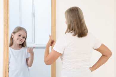Image of Senior woman seeing herself as child in mirror. Conceptual collage about past and future, flow of time, age