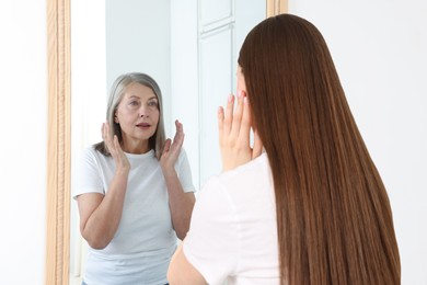 Image of Young girl seeing herself as senior woman in mirror. Conceptual collage about past and future, flow of time, age