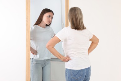 Image of Senior woman seeing herself as young girl in mirror. Conceptual collage about past and future, flow of time, age