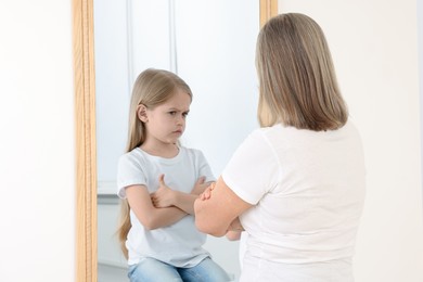 Image of Senior woman seeing herself as child in mirror. Conceptual collage about past and future, flow of time, age
