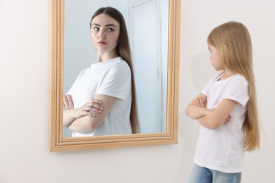 Image of Little girl seeing herself as young woman in mirror. Conceptual collage about past and future, flow of time, age