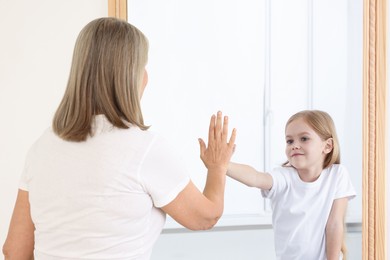 Image of Senior woman seeing herself as child in mirror. Conceptual collage about past and future, flow of time, age