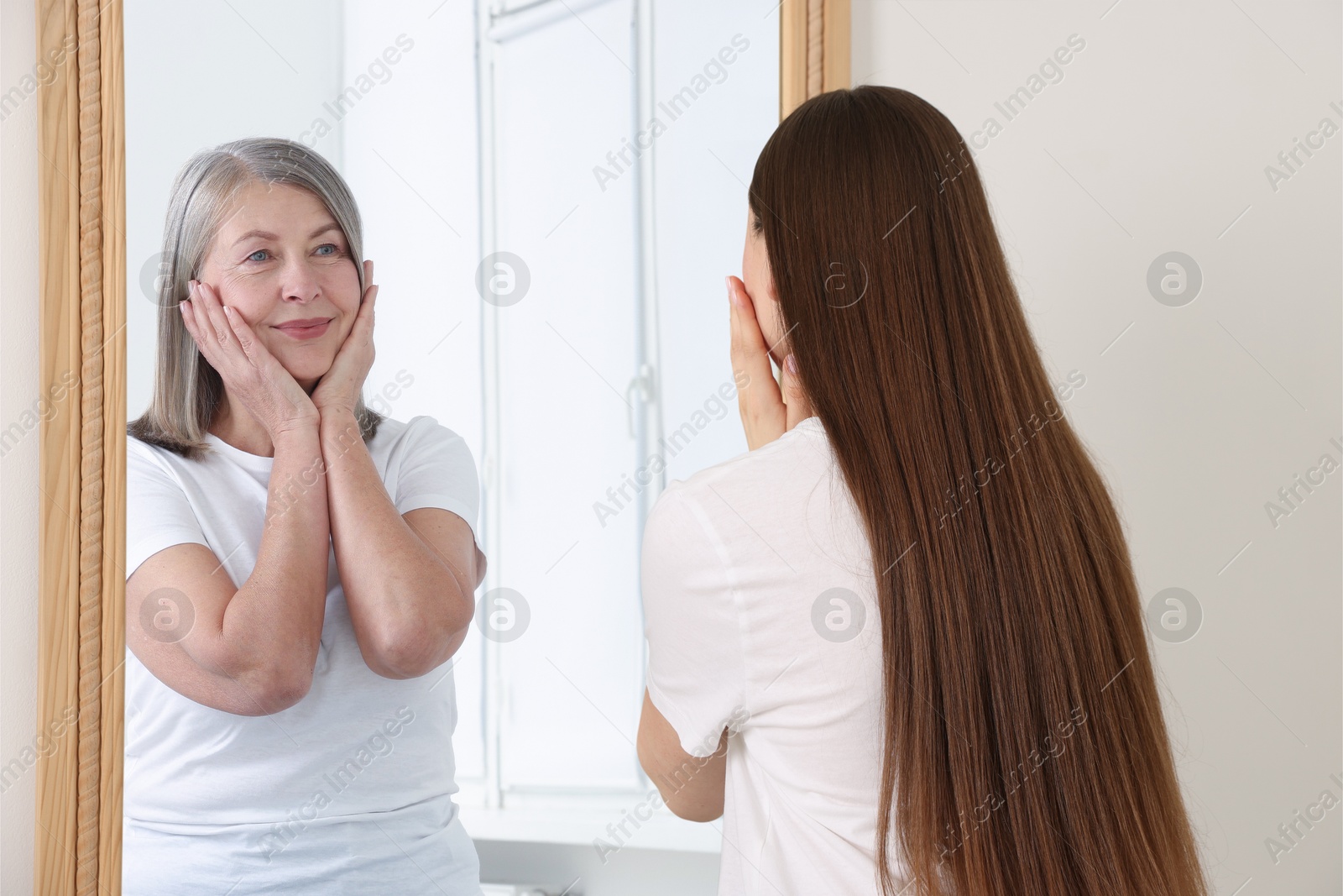 Young girl seeing herself as senior woman in mirror. Conceptual collage about past and future, flow of time, age Image of Young girl seeing herself as senior woman in mirror. Conceptual collage about past and future, flow of time, age
