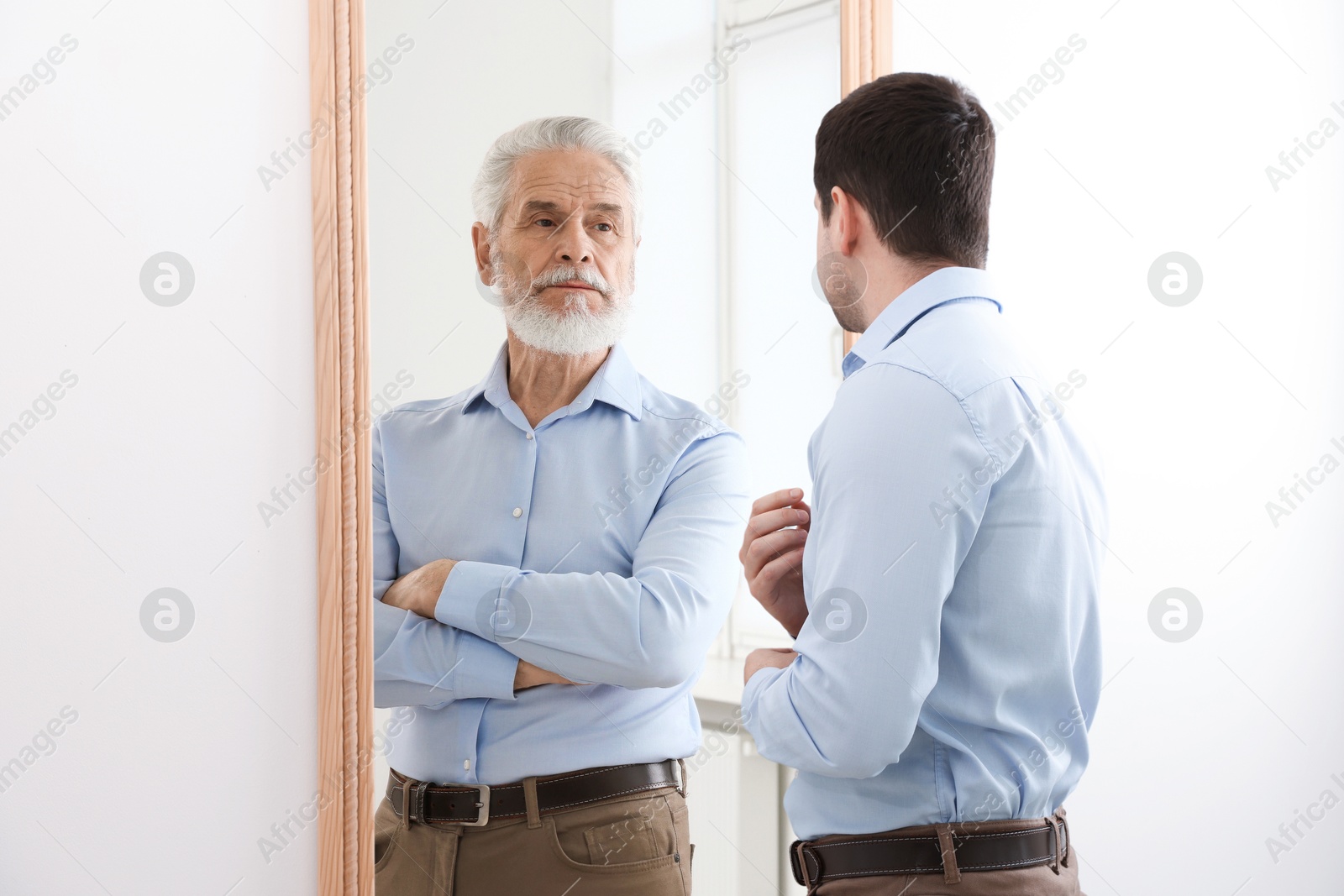 Image of Man seeing himself as elder in mirror. Conceptual collage about past and future, flow of time, age