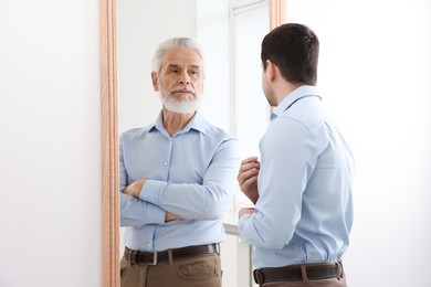 Image of Man seeing himself as elder in mirror. Conceptual collage about past and future, flow of time, age