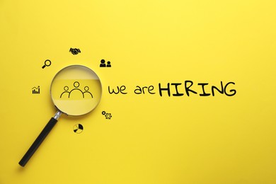 Image of We are hiring. Inscription, icons and magnifying glass on yellow background, top view