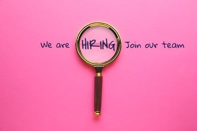 Image of We are hiring, join our team. Inscription and magnifying glass on pink background, top view
