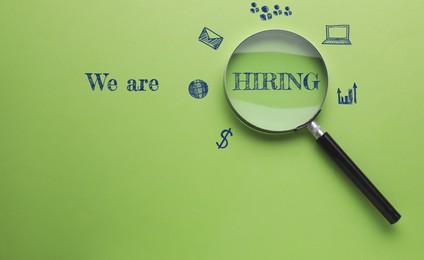 Image of We are hiring. Inscription, icons and magnifying glass on green background, top view