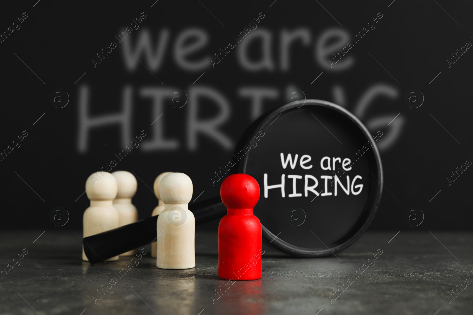 Image of We are hiring. Magnifying glass with inscription inside and human figures on table