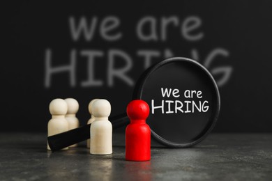 Image of We are hiring. Magnifying glass with inscription inside and human figures on table