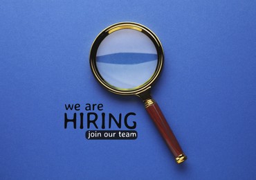 Image of We are hiring, join our team. Inscription and magnifying glass on blue background, top view
