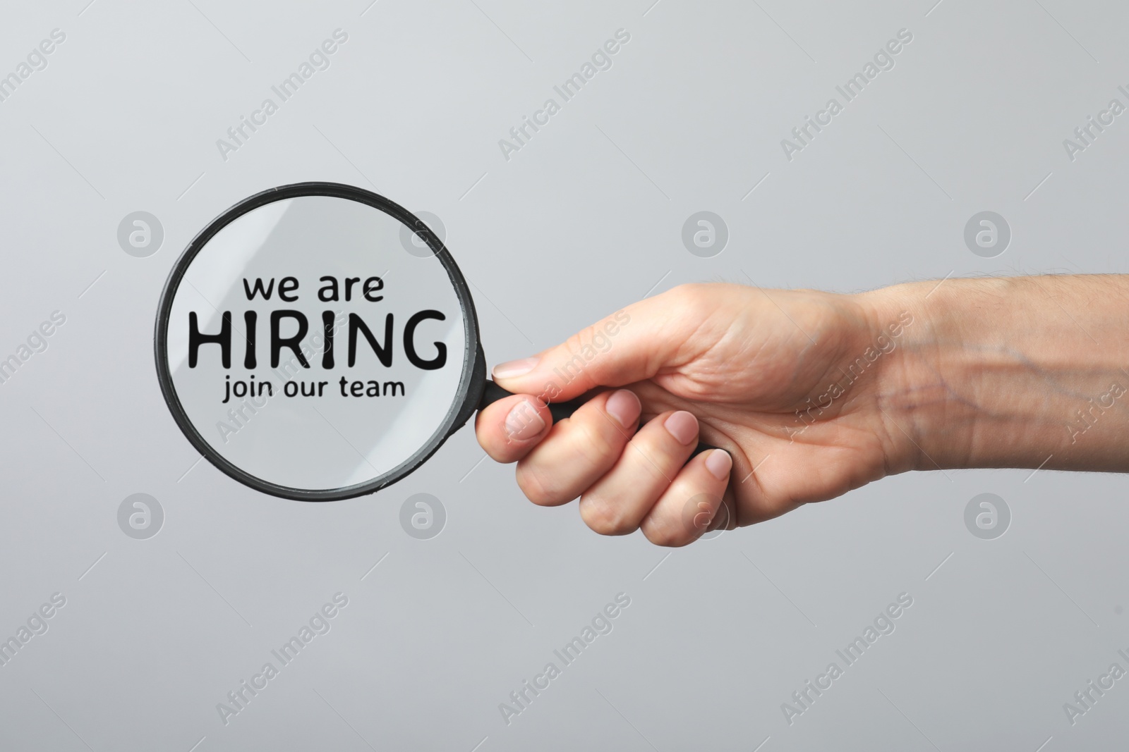 Image of We are hiring, join our team. Woman holding magnifying glass with inscription inside on grey background, closeup