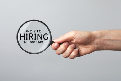 Image of We are hiring, join our team. Woman holding magnifying glass with inscription inside on grey background, closeup