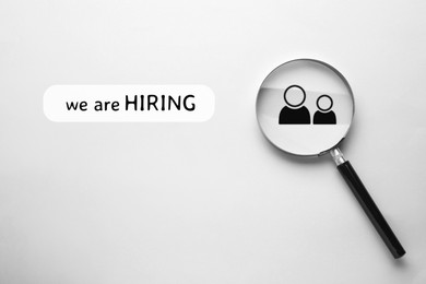 Image of We are hiring. Magnifying glass with human icon and inscription on white background, top view