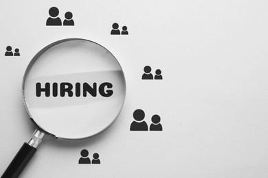 Image of Word Hiring and human icons on white background, view through magnifying glass