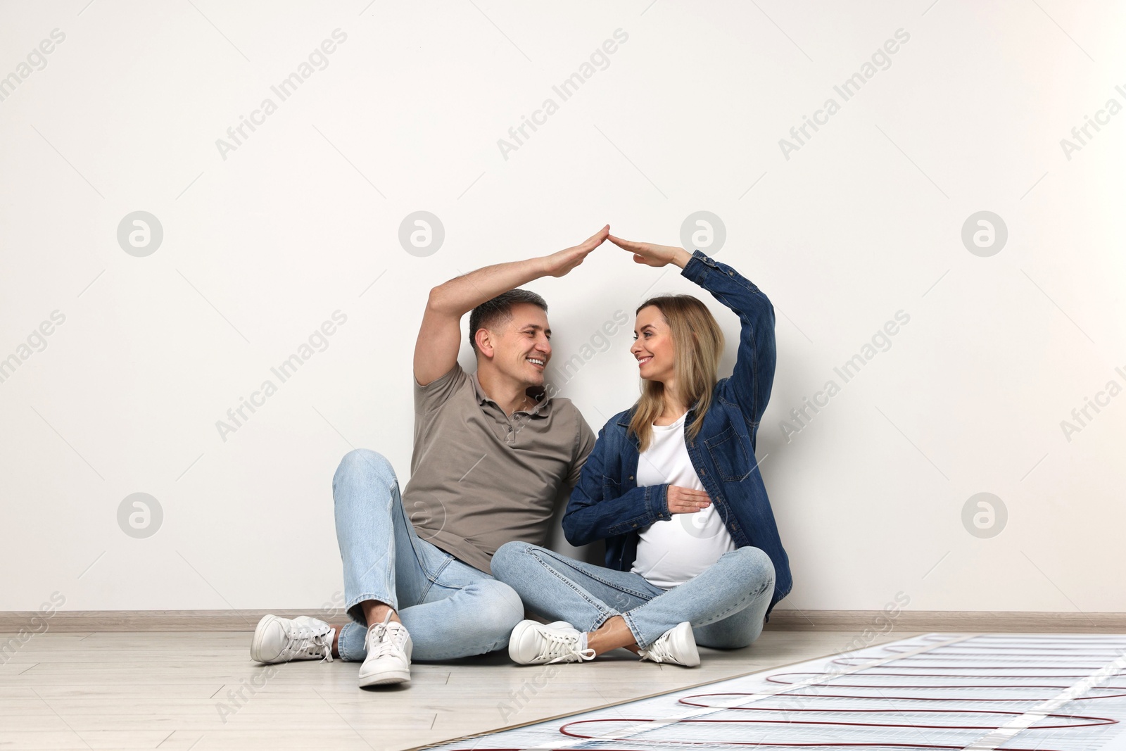 Pregnant woman and her husband on warm floor at home, double exposure with underfloor heating system Image of Pregnant woman and her husband on warm floor at home, double exposure with underfloor heating system