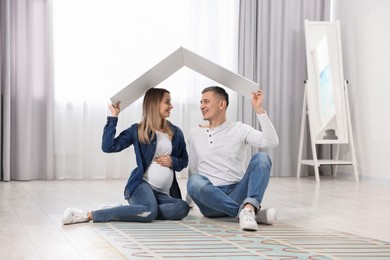 Image of Pregnant woman and her husband on warm floor at home, double exposure with underfloor heating system
