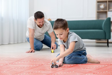 Image of Father and son playing on warm floor at home, double exposure with underfloor heating system