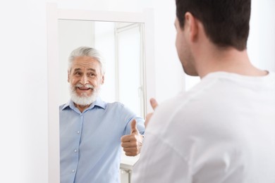 Image of Man seeing himself as elder in mirror. Conceptual collage about past and future, flow of time, age