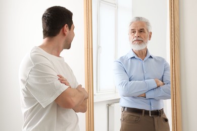 Image of Man seeing himself as elder in mirror. Conceptual collage about past and future, flow of time, age