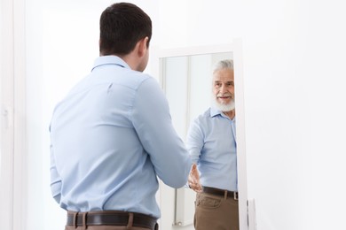 Image of Man seeing himself as elder in mirror. Conceptual collage about past and future, flow of time, age