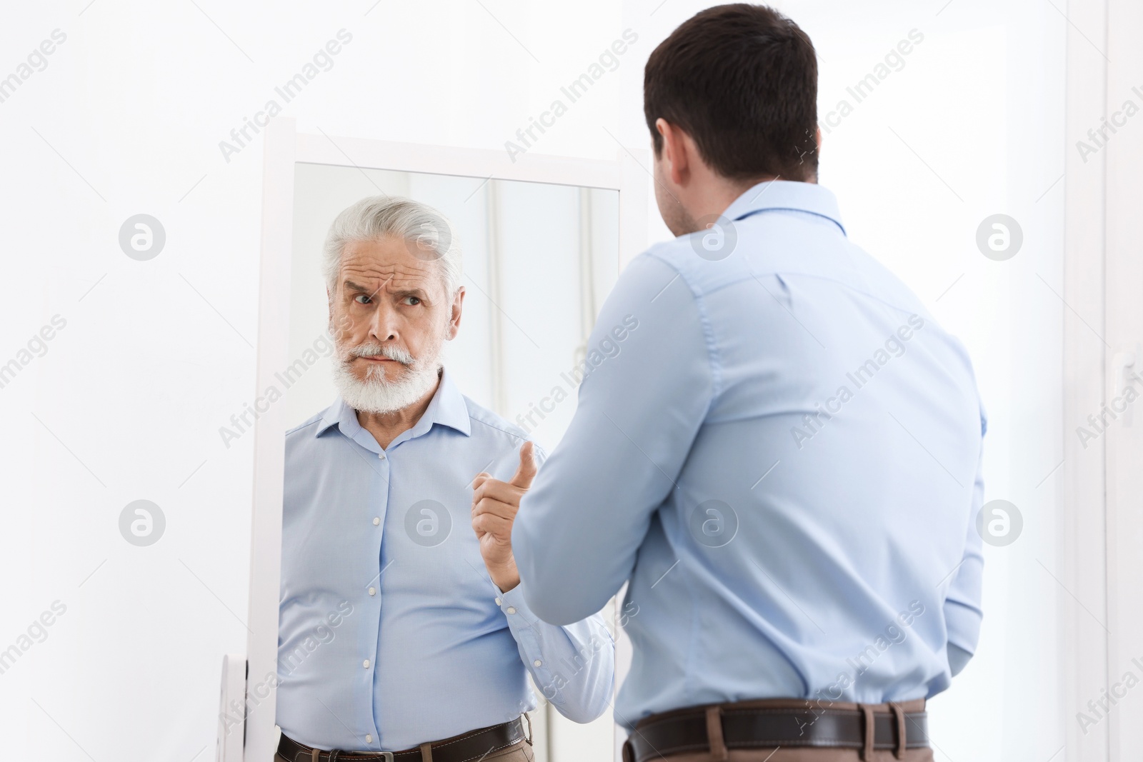 Image of Man seeing himself as elder in mirror. Conceptual collage about past and future, flow of time, age