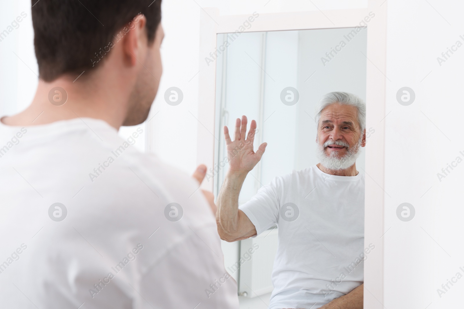 Image of Man seeing himself as elder in mirror. Conceptual collage about past and future, flow of time, age