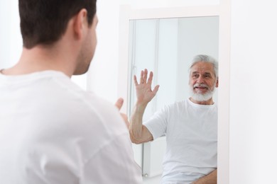 Image of Man seeing himself as elder in mirror. Conceptual collage about past and future, flow of time, age