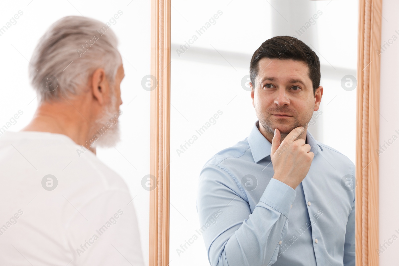 Image of Senior man seeing himself younger in mirror. Conceptual collage about past and future, flow of time, age