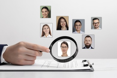 Image of Recruiter looking at candidate's photo through magnifying glass at table, closeup. Human resources management