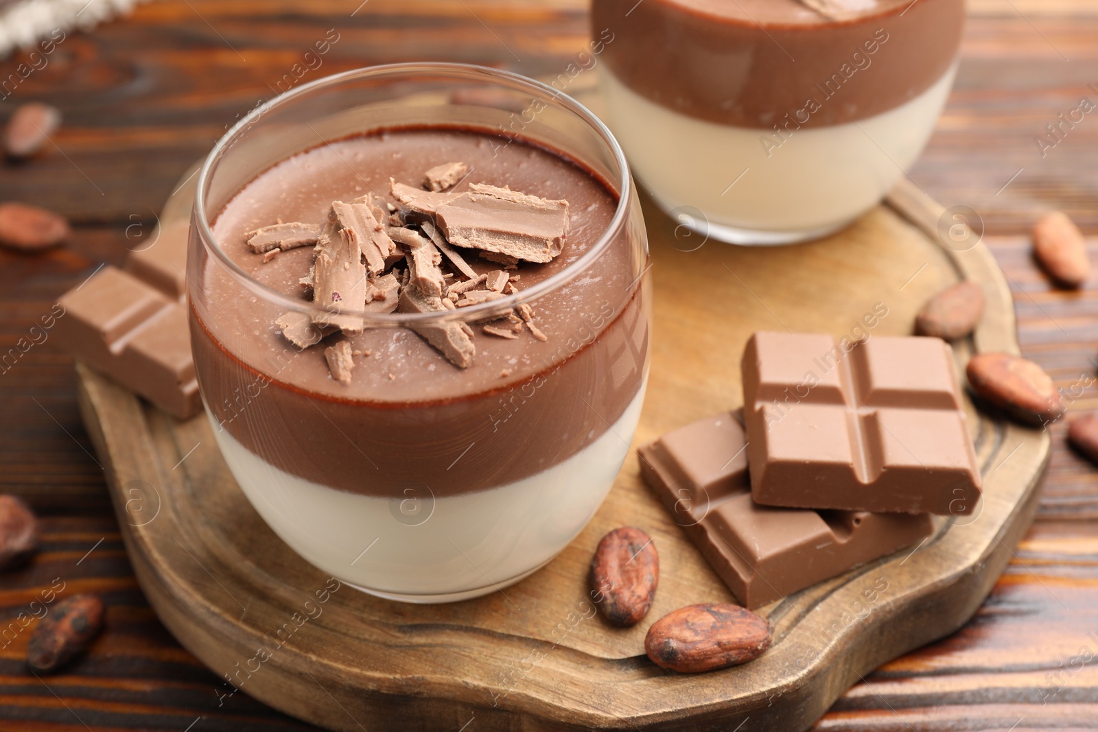 Photo of Delicious panna cotta with chocolate and cocoa beans on wooden table, closeup