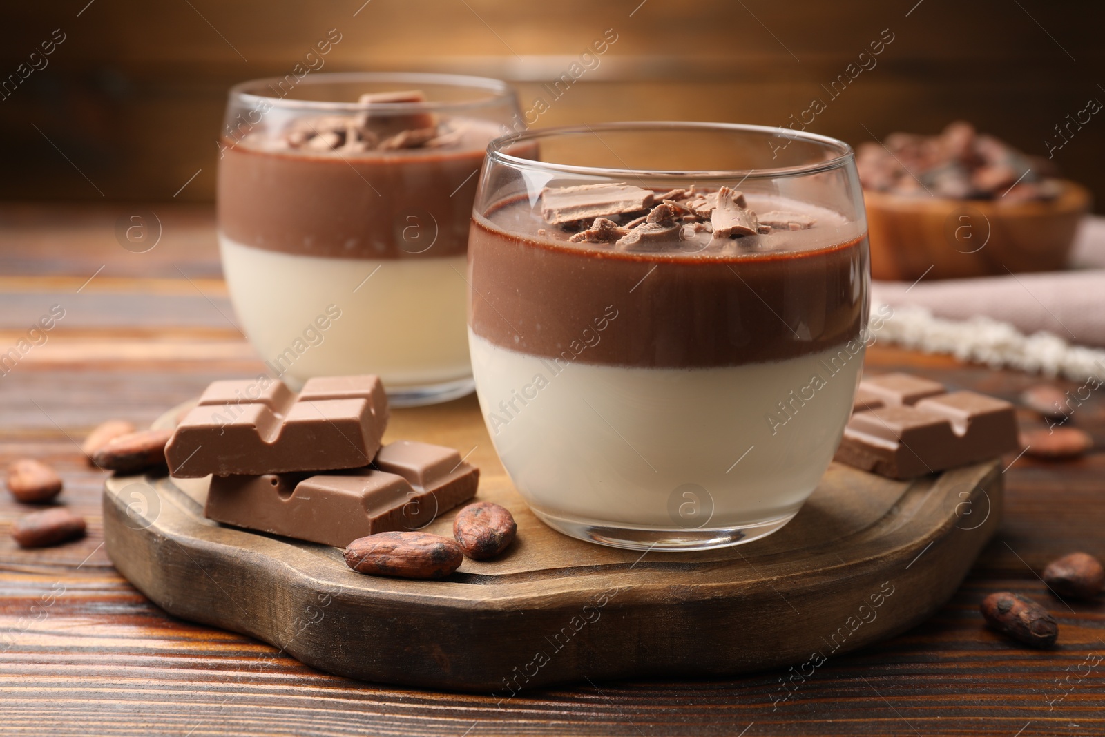 Photo of Delicious panna cotta with chocolate and cocoa beans on wooden table, closeup