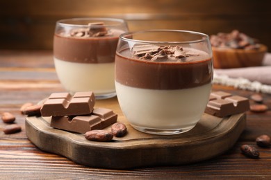 Photo of Delicious panna cotta with chocolate and cocoa beans on wooden table, closeup