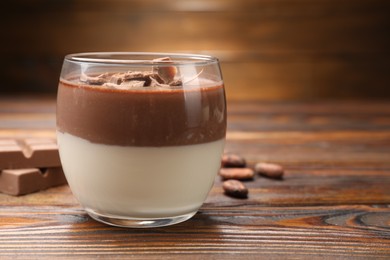 Photo of Delicious panna cotta with chocolate on wooden table, closeup. Space for text