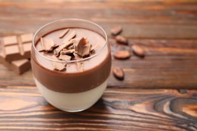 Photo of Delicious panna cotta with chocolate on wooden table, closeup. Space for text