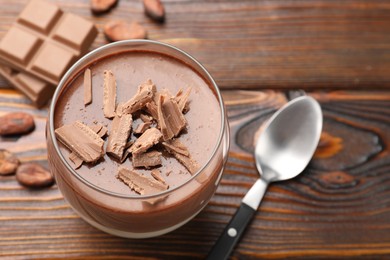 Photo of Delicious chocolate panna cotta in glass on wooden table, closeup