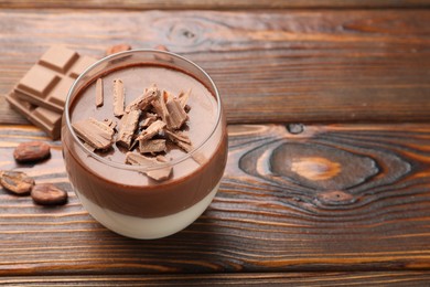 Photo of Delicious panna cotta with chocolate on wooden table, closeup. Space for text