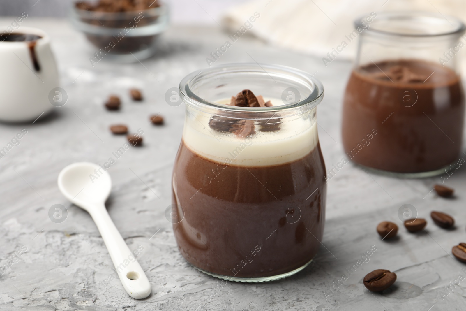 Photo of Delicious panna cotta and coffee beans on grey textured table, closeup