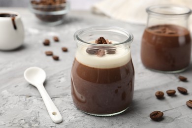 Photo of Delicious panna cotta and coffee beans on grey textured table, closeup