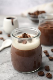Photo of Delicious panna cotta and coffee beans on grey textured table, closeup