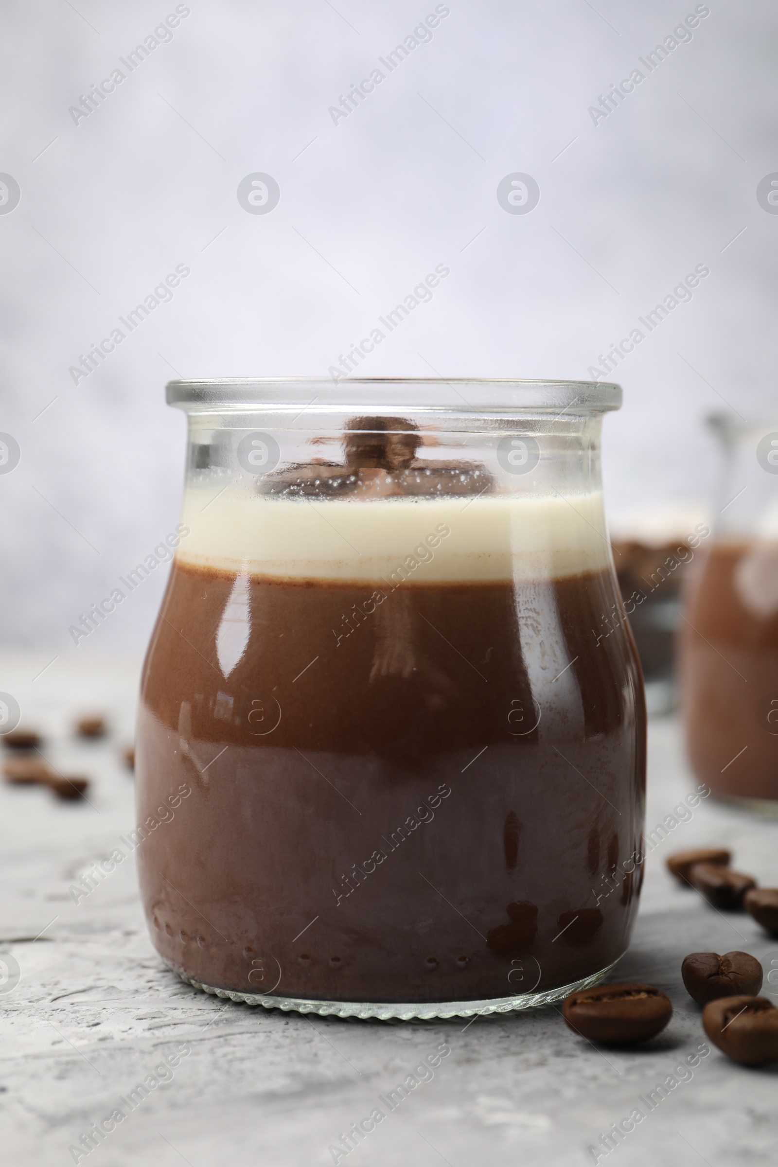 Delicious panna cotta and coffee beans on grey textured table, closeup Photo of Delicious panna cotta and coffee beans on grey textured table, closeup