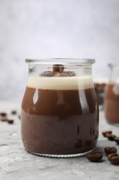 Photo of Delicious panna cotta and coffee beans on grey textured table, closeup