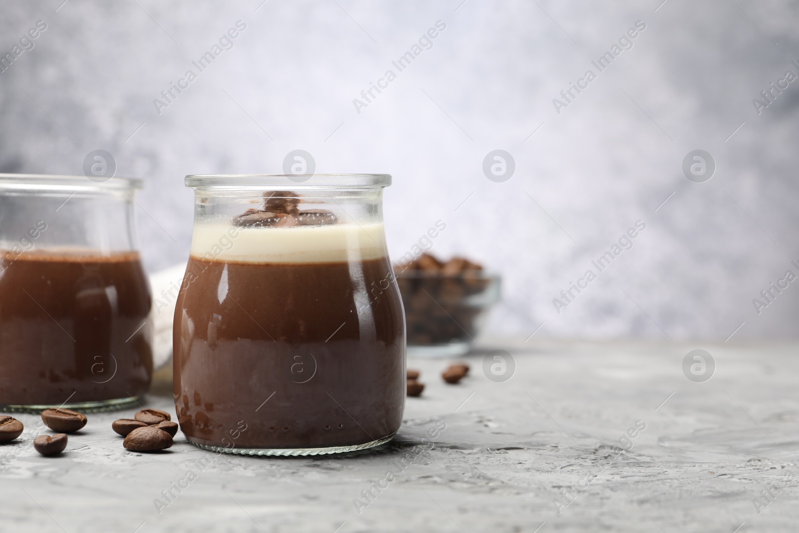 Photo of Delicious panna cotta and coffee beans on grey textured table, closeup. Space for text