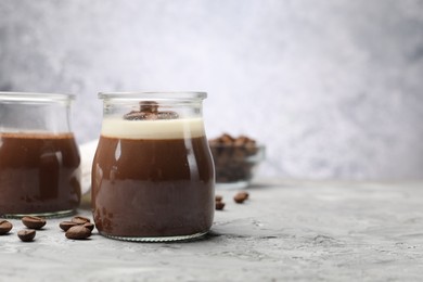 Photo of Delicious panna cotta and coffee beans on grey textured table, closeup. Space for text