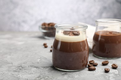 Photo of Delicious panna cotta and coffee beans on grey textured table, closeup. Space for text