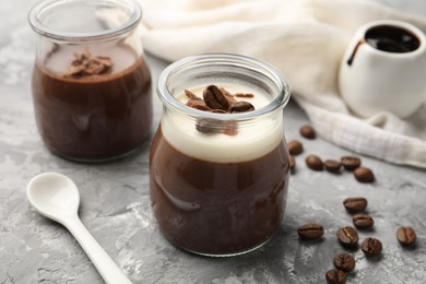 Photo of Delicious panna cotta with chocolate chunks and coffee beans on grey textured table, closeup