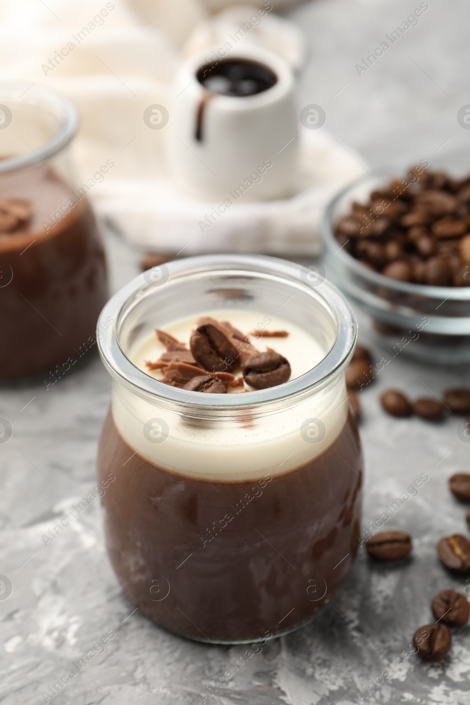 Photo of Delicious panna cotta with chocolate chunks and coffee beans on grey textured table, closeup