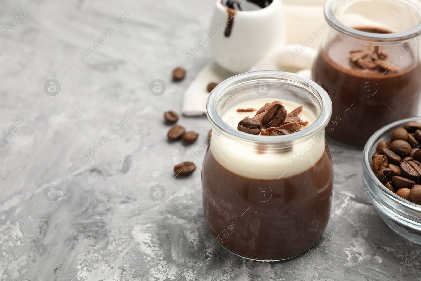 Delicious panna cotta with chocolate chunks and coffee beans on grey textured table, closeup. Space for text Photo of Delicious panna cotta with chocolate chunks and coffee beans on grey textured table, closeup. Space for text